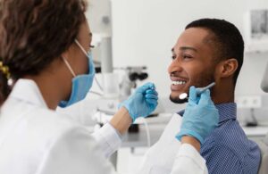 A dental hygienist cleans a patient's teeth using specialized tools in a bright, modern dental office.