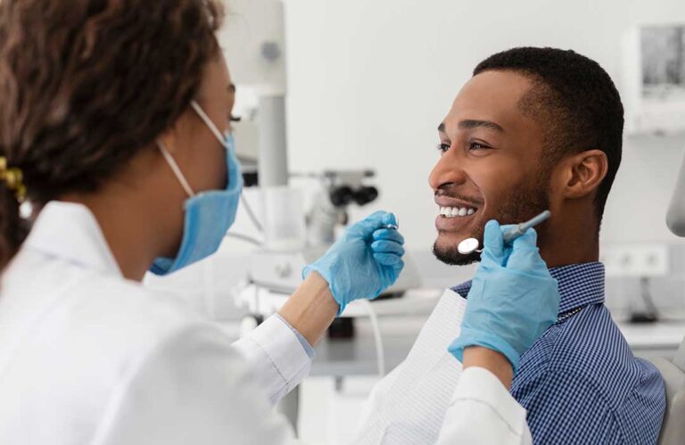 A dental hygienist cleans a patient's teeth using specialized tools in a bright, modern dental office.
