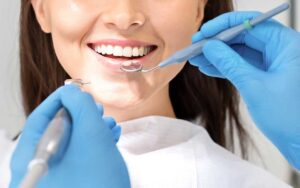 Teenager brushing around metal braces in a bathroom mirror with an interdental brush nearby.